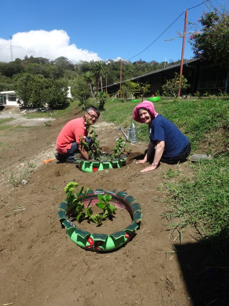 Teacher Jorge and Global Volunteer Sharon planting in the newly painted tires in Costa Rica