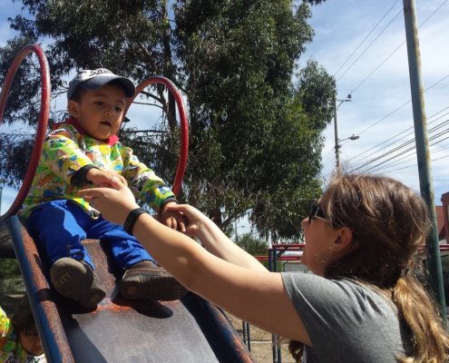 Global Volunteer Alyssa Peiffer helping child on slide in Ecuador