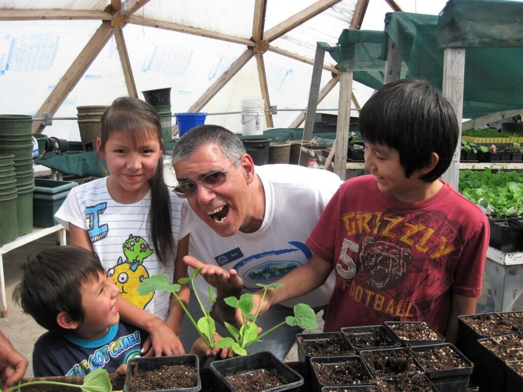 Volunteer Barry Sirini with children from the Blackfeet reservation working with seedlings at a greenhouse.