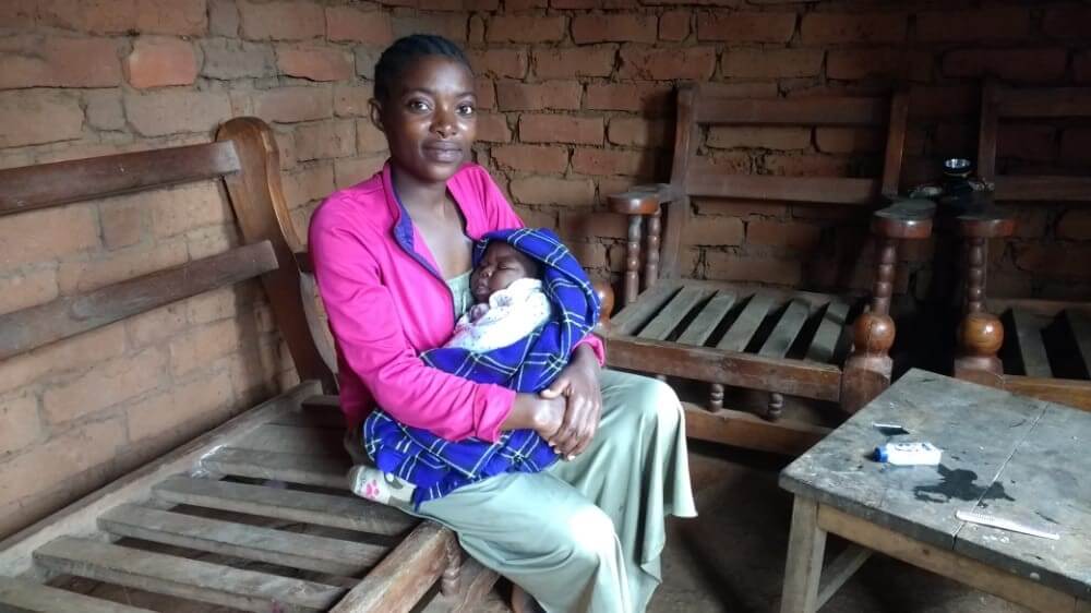 woman cares for baby village tanzania