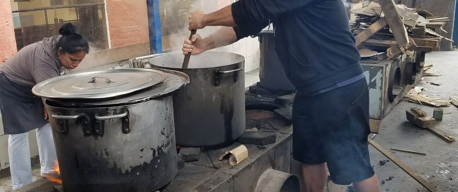 Volunteer stirs pots over wood stove peru