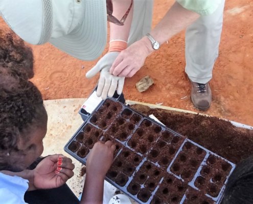 A volunteers help the local people in Tanzania plant quality seeds.