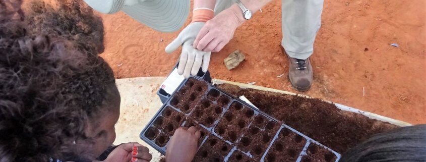 A volunteers help the local people in Tanzania plant quality seeds.
