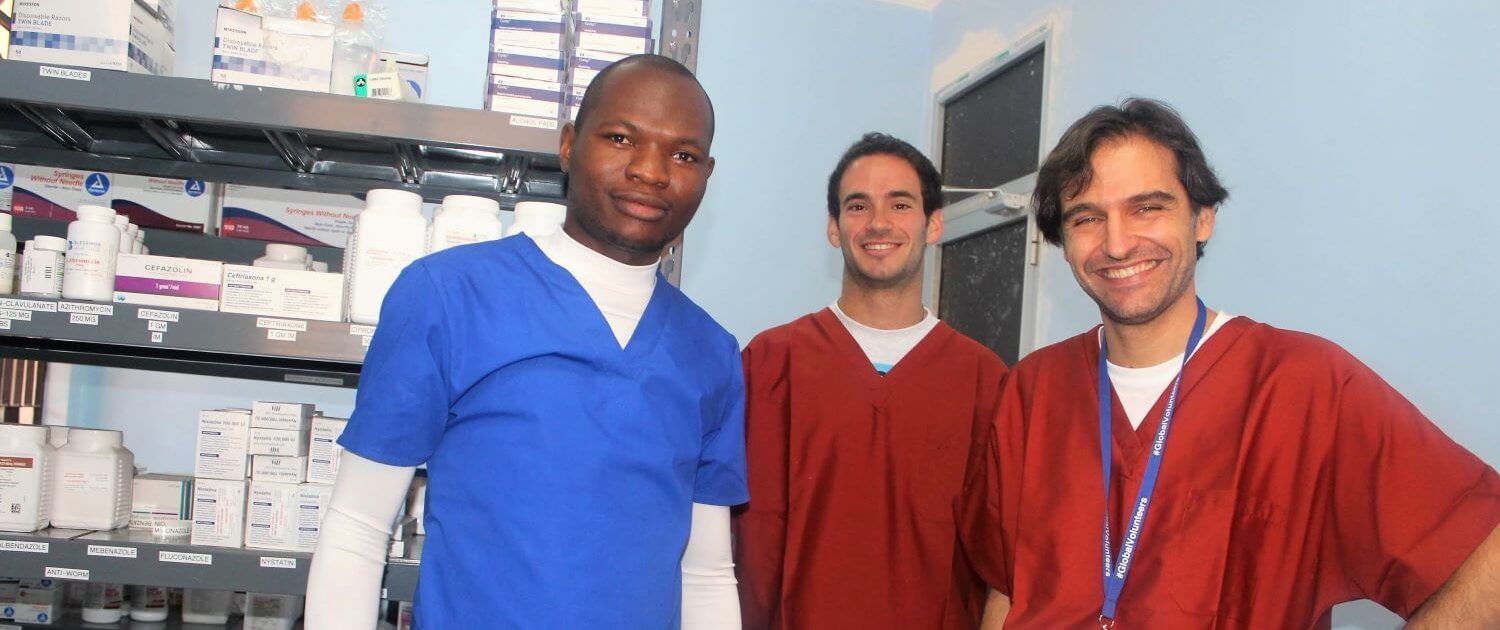 volunteers Salvador Ramos and Javier Bernat in the pharmacy with the local nurse practitional at clinic tanzania