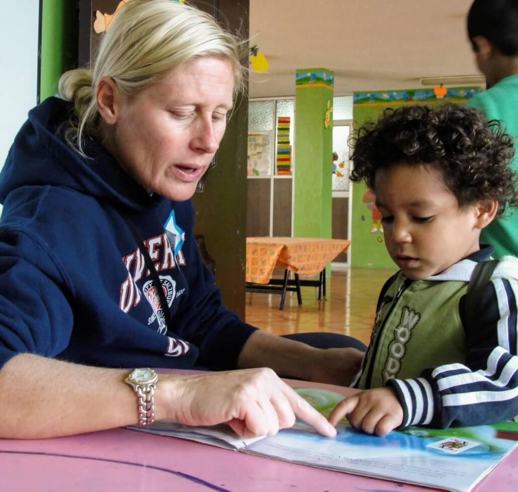 Volunteer reading a story book to a toddler in Ecuador.