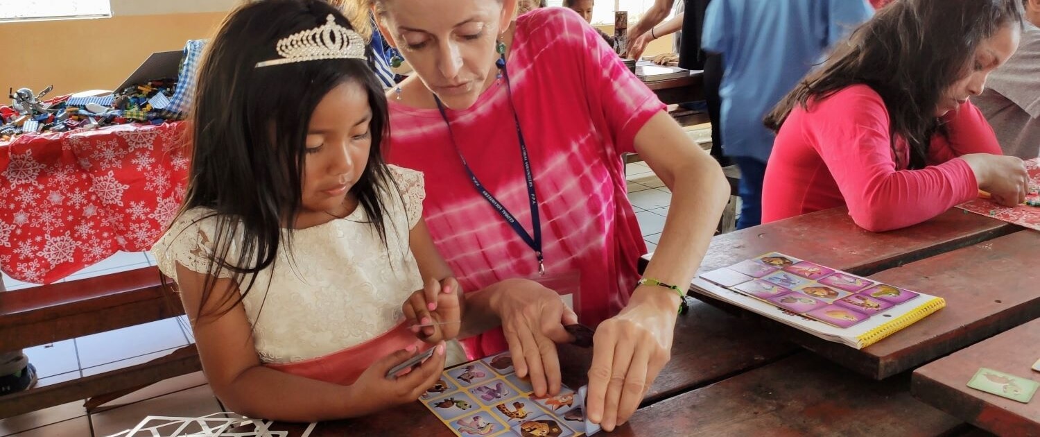 Volunteer plays memory game with toddler in Peru. 