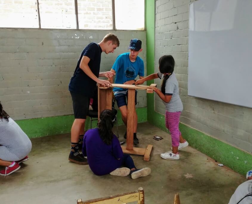 Volunteers repairing desks school girls Sagrada Familia peru
