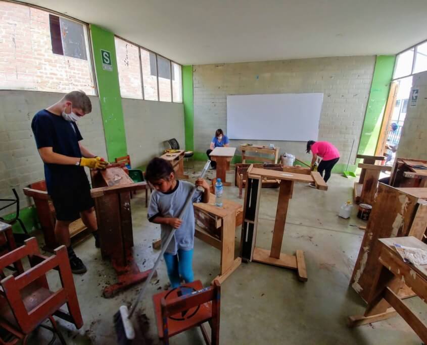 Volunteers repair desks with some school girls at Sagrada Familia Peru