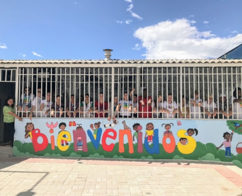 Volunteers and teachers with new mural and renovated exterior of early childhood development Center #1 in ecuador
