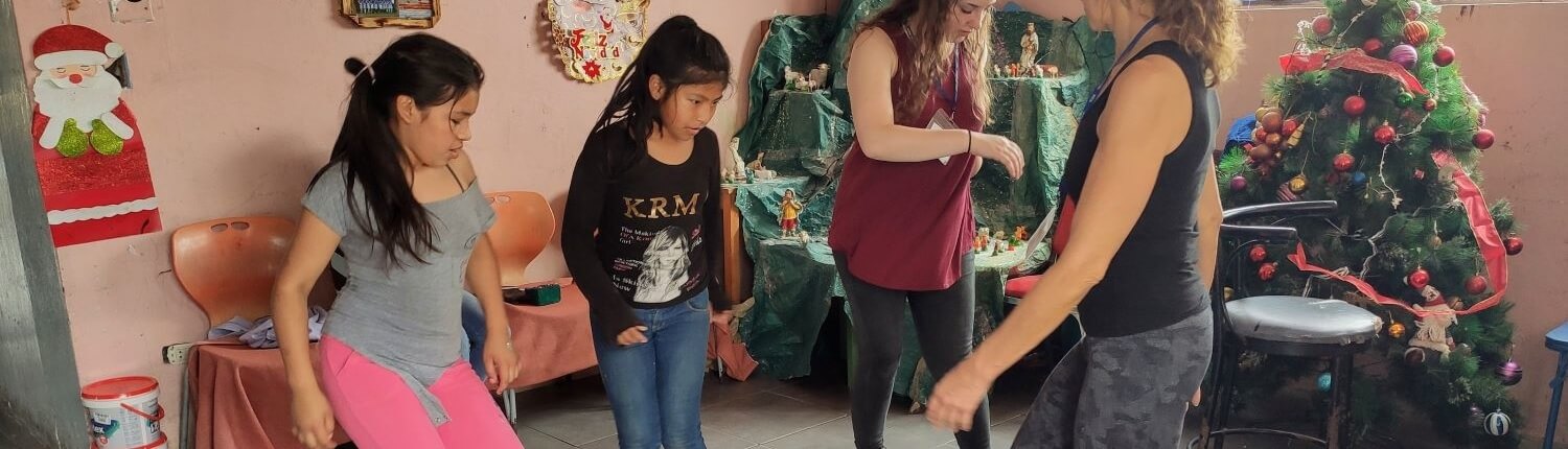 Children in Peru dancing at the Sagrada Familia children's community with volunteers during Christmas season