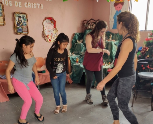 Children in Peru dancing at the Sagrada Familia children's community with volunteers during Christmas season