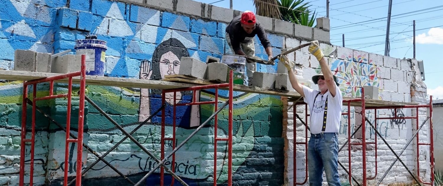Volunteer helps a local worker build a wall on an early childhood development center in Calderón, Ecuador.