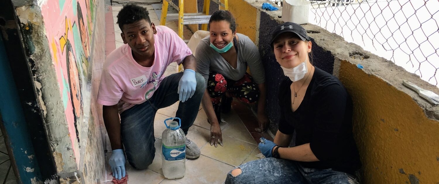 volunteers work with a local mother cleaning the walls of an early childhood development center in Calderón