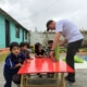 international Volunteer reupholsters seats while children watch an early childhood development center in Calderón, Ecuador.